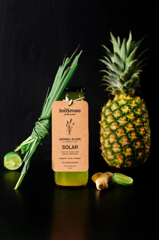 JooSmoo cold-pressed juice with fresh pineapple and green ingredients